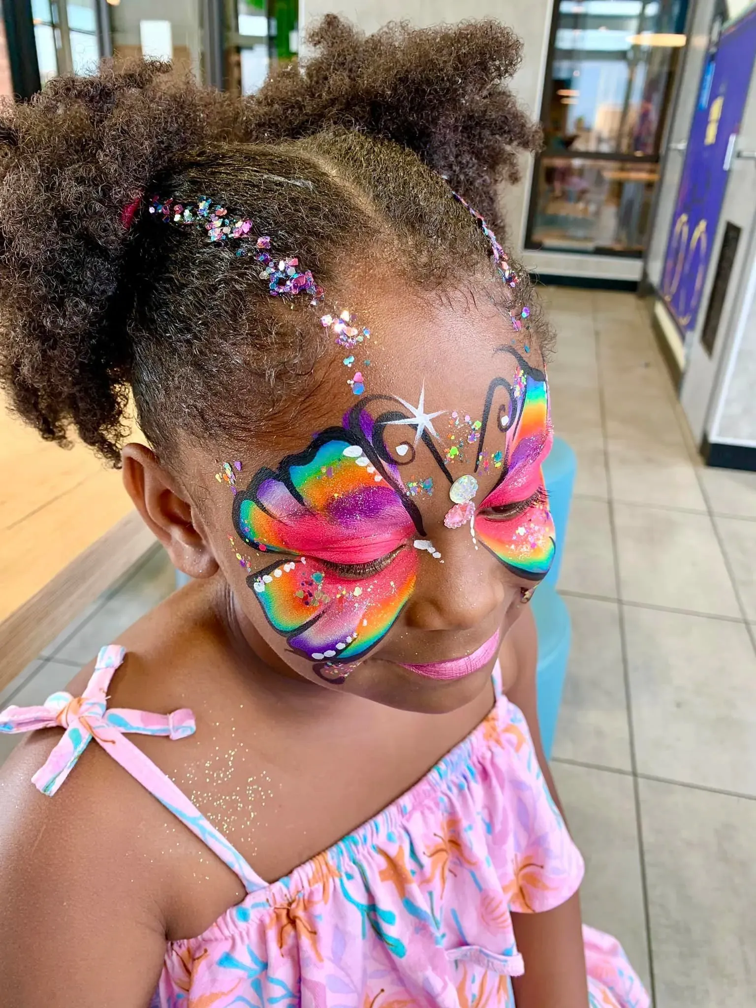 girl with rainbow butterfly sparkle face paint