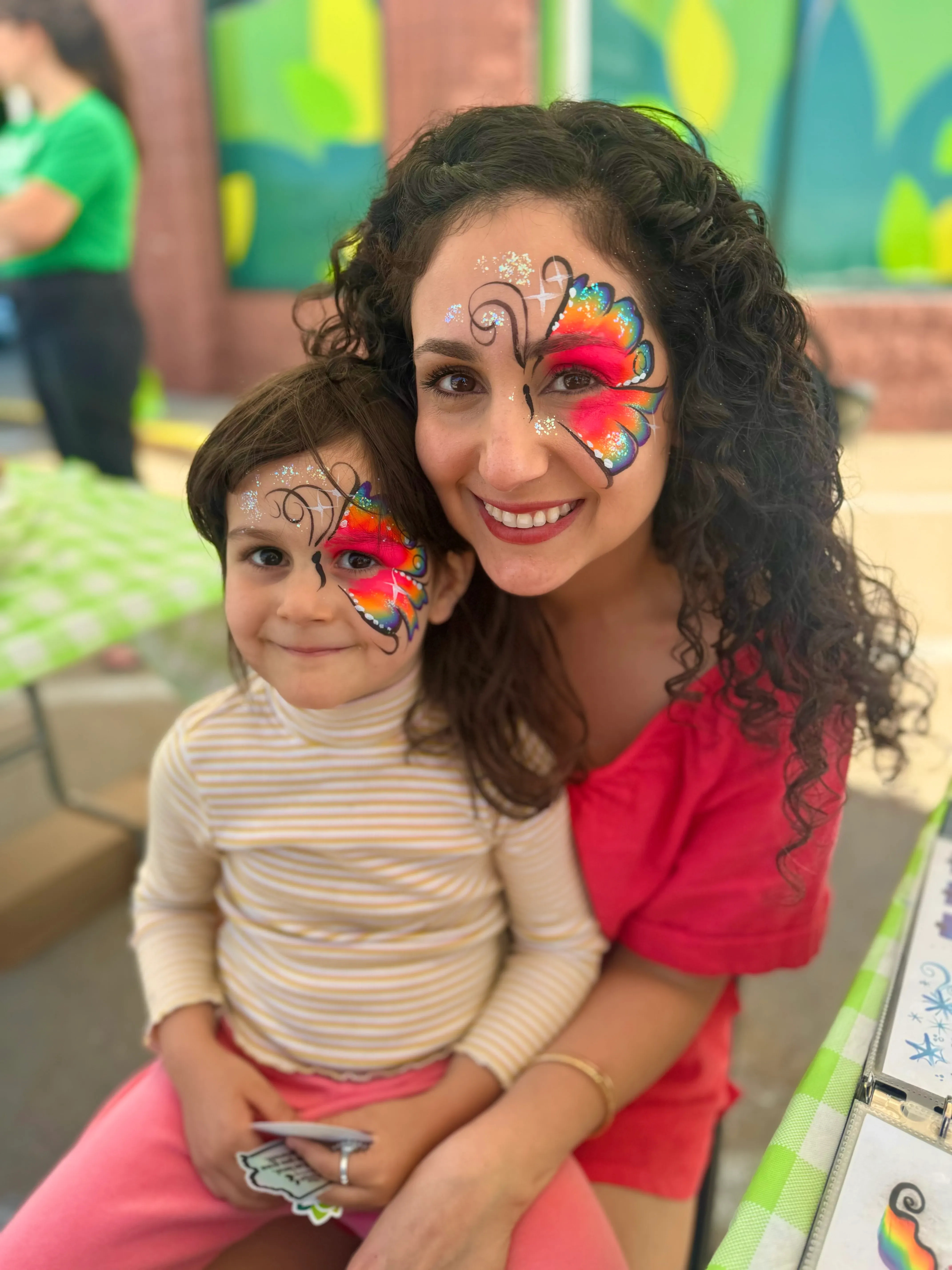 woman and daughter with rainbow flower face paint